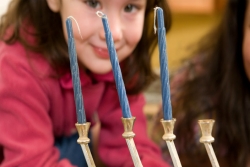 Preschooler looking at hanukkiyah with unlit candles in it